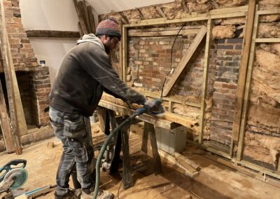 Action shot of jonny at precision build sanding down elm beams in restoration of barn
