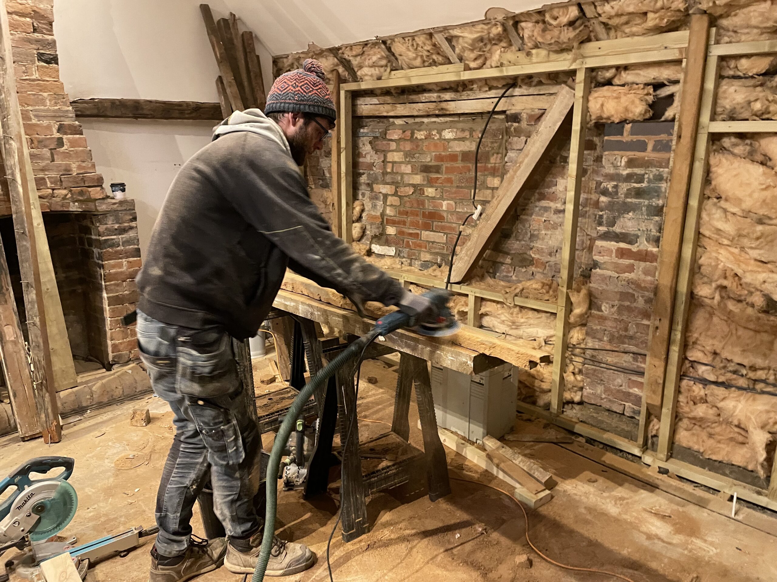 Action shot of jonny at precision build sanding down elm beams in restoration of barn